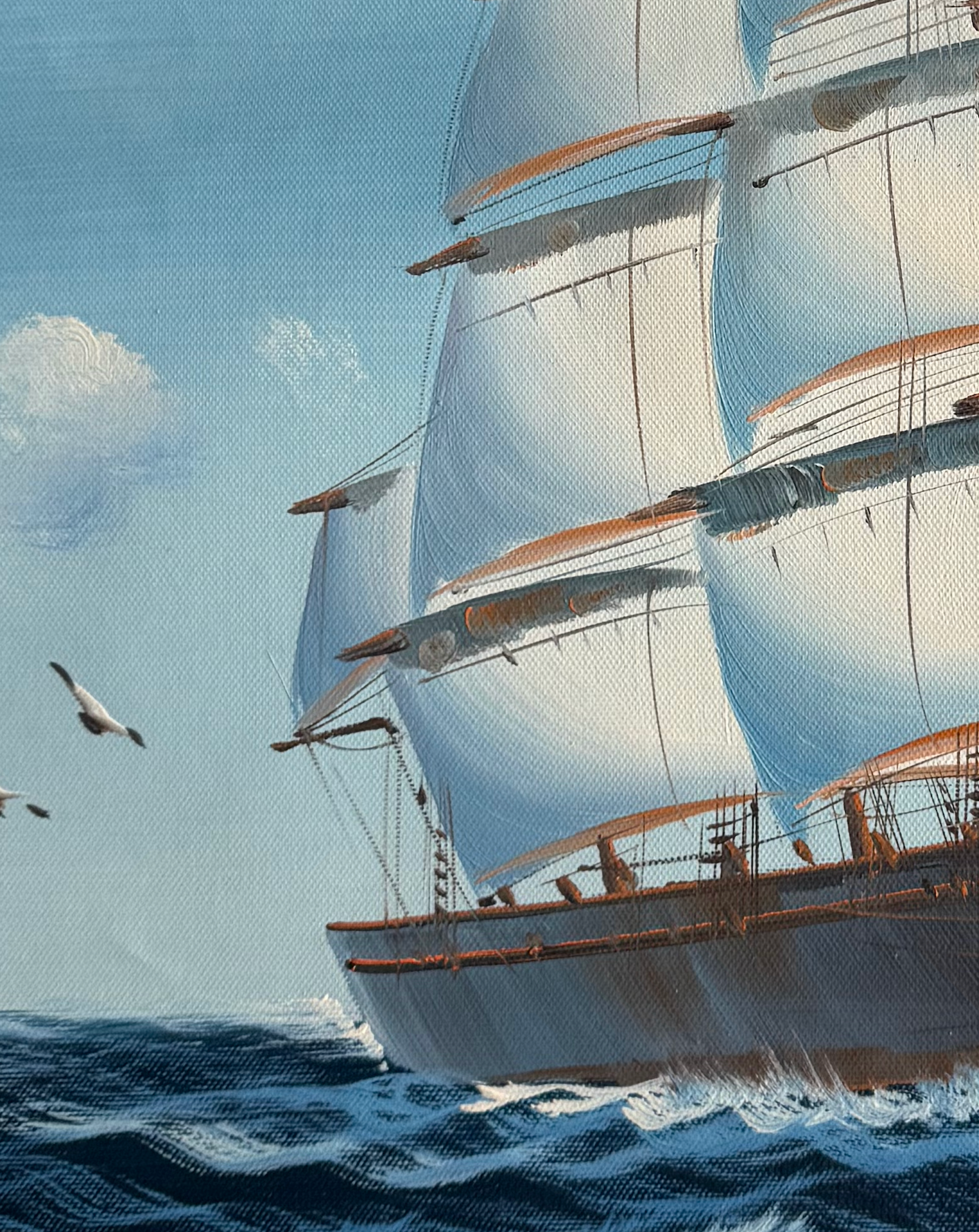 Sailing ship with large sails on a blue ocean with a clear sky.