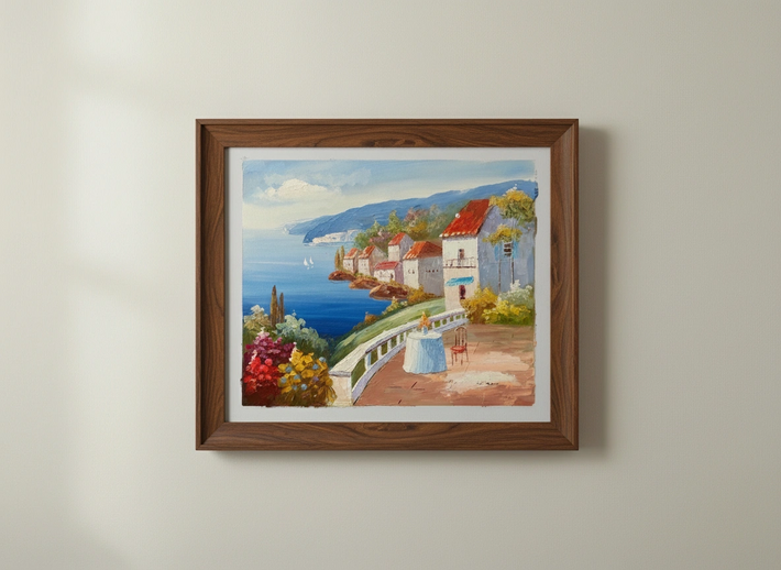 Framed painting of a coastal scene with houses and a blue sky.